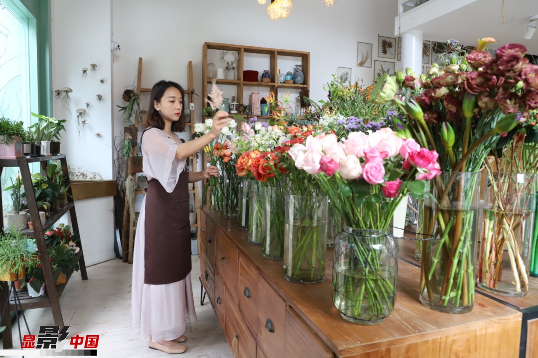 王黎媛是一名河南姑娘，在昆明念完大學(xué)后，就再也舍不下春城的藍(lán)天陽光、青山碧水，更舍不下這里的四時繁花，于是就干脆留了下來，成了一名媒體人。2017年的時候又毅然辭去工作，創(chuàng)業(yè)開起了花店，成了都市里的一名“花房姑娘”。圖為王黎媛在自己的花店中整理鮮花。新華網(wǎng) 周亞平/攝 念新洪/文